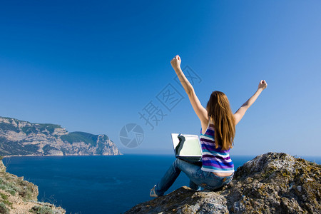 坐在石头上的女人带着笔记本电脑图片