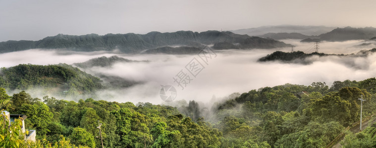 雾和云中电力塔的乡村全景图片