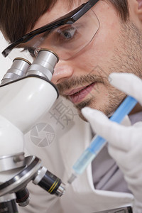 科学研究男在显微镜中用注射图片