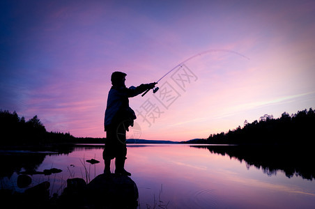 在湖里钓鱼渔夫的剪影图片