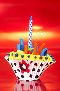 红色背景上带蜡烛的磨砂纸杯蛋糕图片