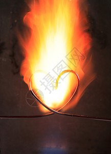 在黑暗的背景下用电线在火中制成的心背景图片