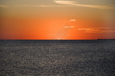 红海的神秘日落黑暗的海面上的太阳五颜六色的天空和云彩图片