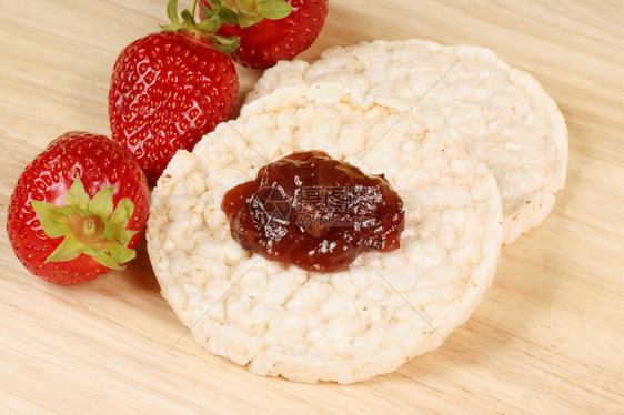 有果酱和新鲜草莓的米饼在木质背景上健康饮图片