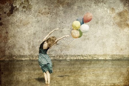 红发女孩带彩色气球在海岸照片以旧图片