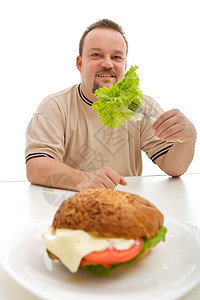健康饮食选择概念即超重男人吃生菜而图片