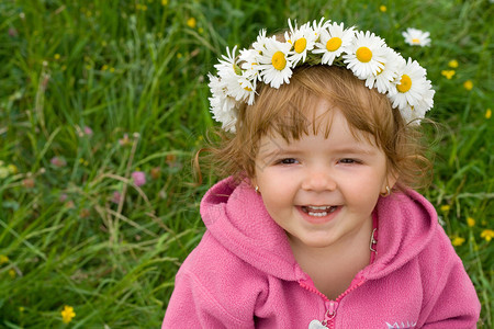 带着花圈的宝贝女孩抬头笑在春泉草地图片