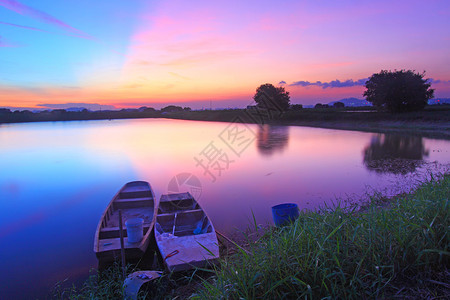 日落时分沿池塘的孤立小船图片