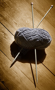 羊毛球和针织在木制背景上图片