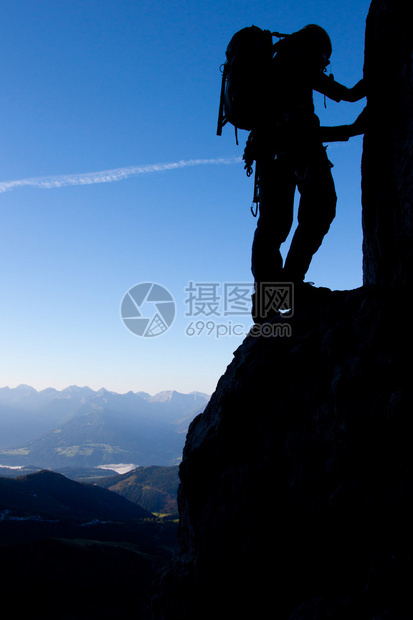 高在山谷上方的登山者的剪影图片