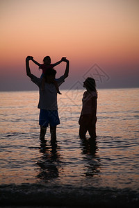 夕阳下海边的一家人图片