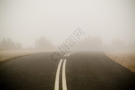 带有双线的黑暗道路消失在非常浓密的雾中图片