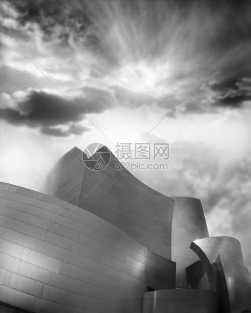 深色多云天空上金属现代弯曲建筑的图片