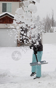 雪中西装的女人在暴风雪过后铲图片