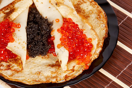 盘子里有红色和黑色鱼子酱的煎饼图片