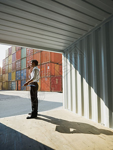 中间成年商人在货集装箱附近说话的肖像垂直形状侧视图图片