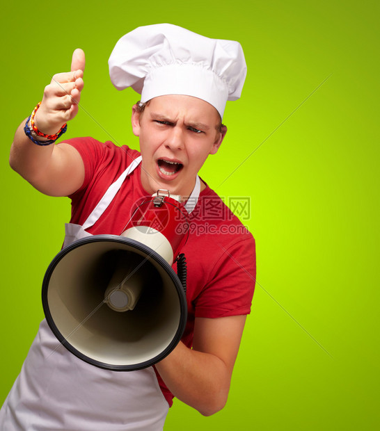 年轻厨师用扩音喇叭尖叫在绿色背景图片