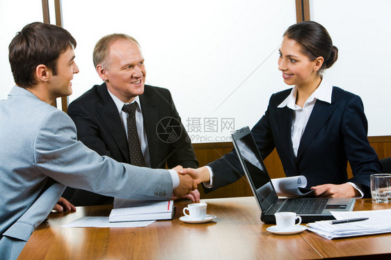 自信的伙伴坐在桌边握手图片
