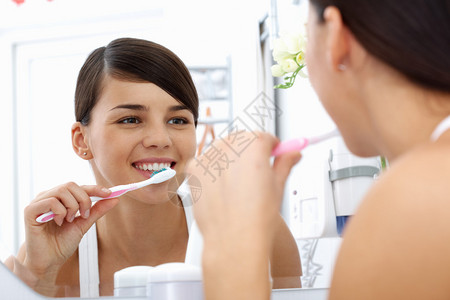 在镜子前刷牙的年轻美少女正图片