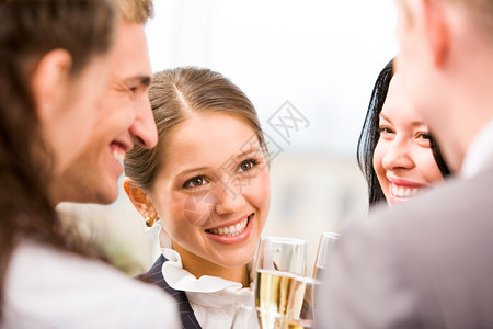 欢乐的女子在派对期间拿着长笛香槟和对同背景图片