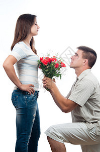 英俊的年轻帅气的男人恳求宽恕并献一束玫瑰背景图片