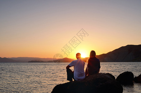 女孩和男孩坐在海边的岩石图片