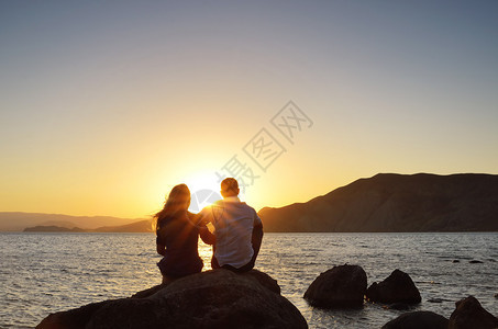 小情侣坐在海边的岩石上看图片