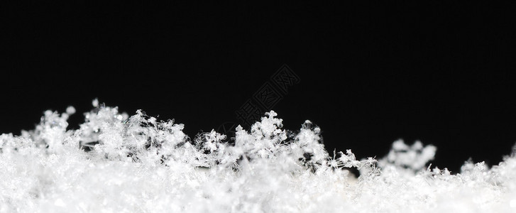 黑色冬季全景中带有黑色雪晶的小白色背景图片