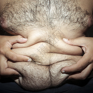 腹部脂肪和毛茸的人用手图片