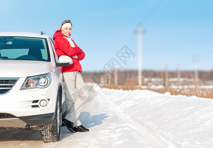 穿着红色夹克的年轻女孩站在白色的大车旁微笑着与美丽的女人的愉快的公路旅行积极的户外和冬季驾车旅行明亮的一天图片