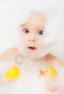 用橡皮鸭沐浴在肥皂水中的小女婴背景图片