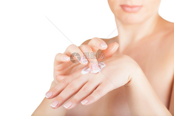 年轻女用奶油涂在她手上的白色背景上图片