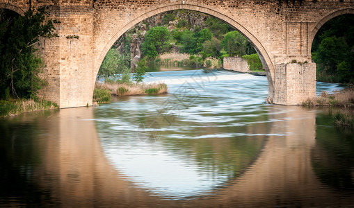 位于西班牙托莱多的著名桥拱门和水面反射形成大圆圈河流运行迅速美丽的自然图片
