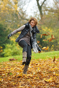 欧洲女人在秋天踢黄叶图片
