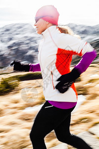 年轻女子在冬天秋阳光明媚的日子在山上奔跑女跑步者在大自然中户图片