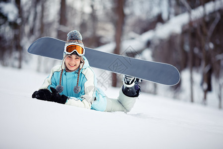 年轻美丽的女滑雪板选手躺在滑雪坡上她躺图片