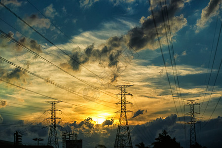 高压输电线的剪影背景是暴风雨云和夕阳图片