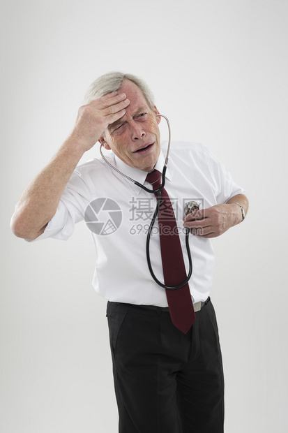 感觉不适的老人正试图在听诊器的帮助下诊图片