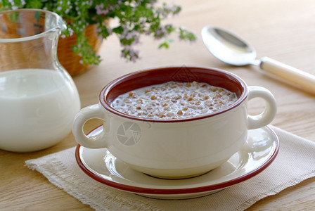 木桌上碗里的牛奶荞麦粥图片