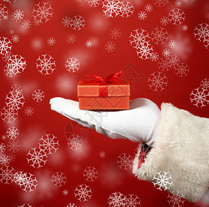 圣诞老人戴着手套的手和红色小礼盒的创意照片图片
