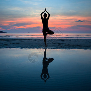 年青女子在海岸日落时做瑜伽图片