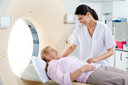放射技术员对躺在CT扫描床上的成熟女病图片