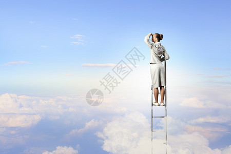 商业妇女站在梯子上寻找远离云层背景图片