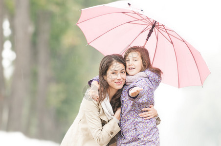 年轻漂亮的女人带着漂亮的小女儿在公园里的伞下母亲和女儿在一起友好图片