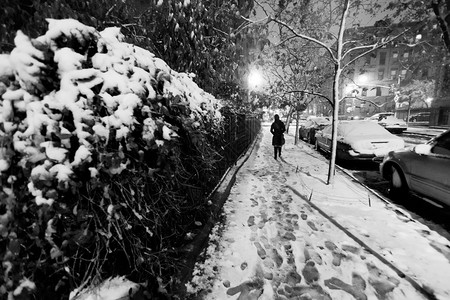 在雪上行走的单身女人在一个冰冷的暴风雪之夜在哈林街背景图片