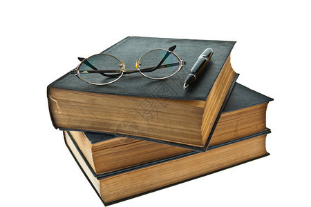 白色背景的旧书堆叠着眼镜和笔孤图片