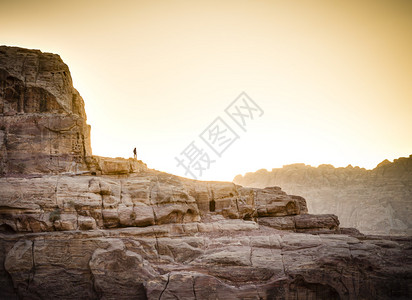 孤独的徒步旅行者在日落时站在约旦佩特拉的岩石上图片