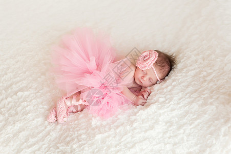 一位身着粉红编织头带和围裙的入睡新生女婴在空中露面图片