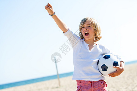 男孩的肖像站在沙滩上足球图片