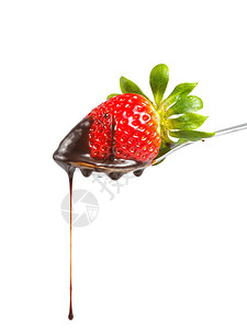 用勺子把巧克力糖浆倒在草莓上图片